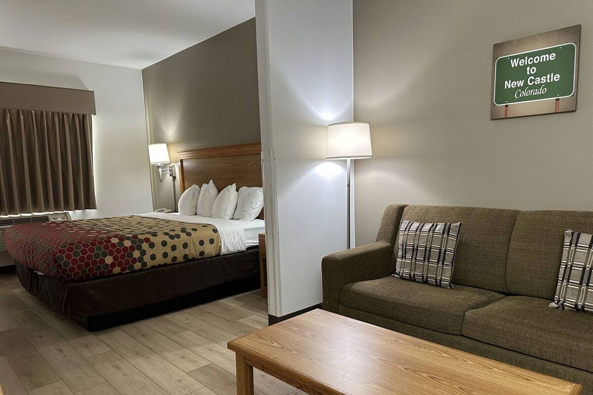 Une chambre d’hôtel avec un lit, un canapé, une table basse et une lampe.