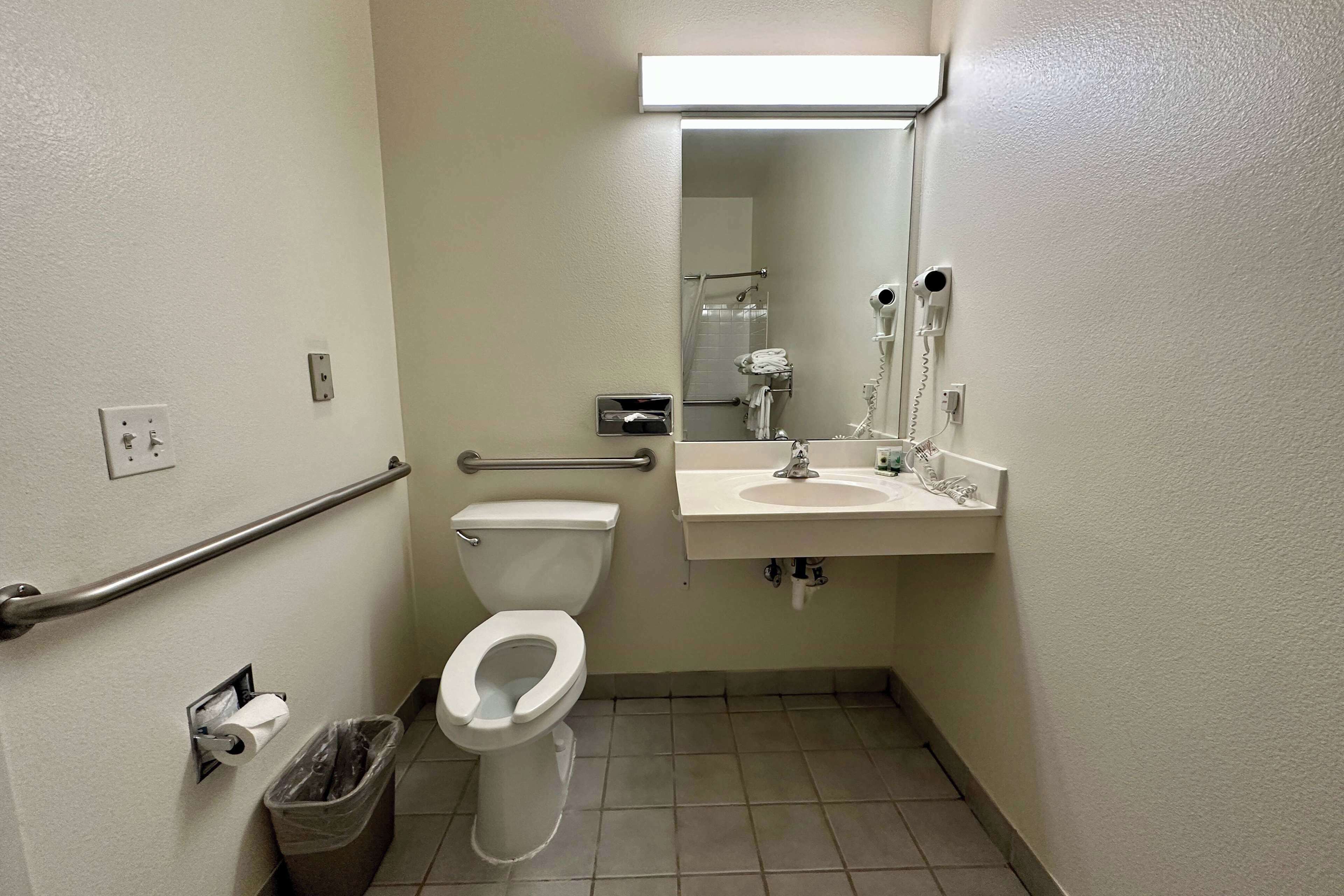 A small, clean bathroom with a toilet, sink, and hand dryer.