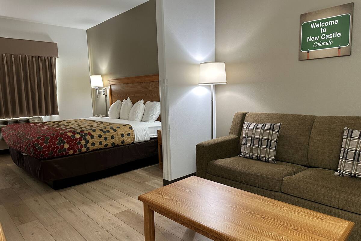 Une chambre d’hôtel avec un lit, un canapé, une table basse et une lampe.