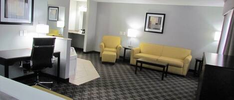 Ein Hotelzimmer mit Bett, Schreibtisch, Sessel, Sofa und kleinem Tisch.