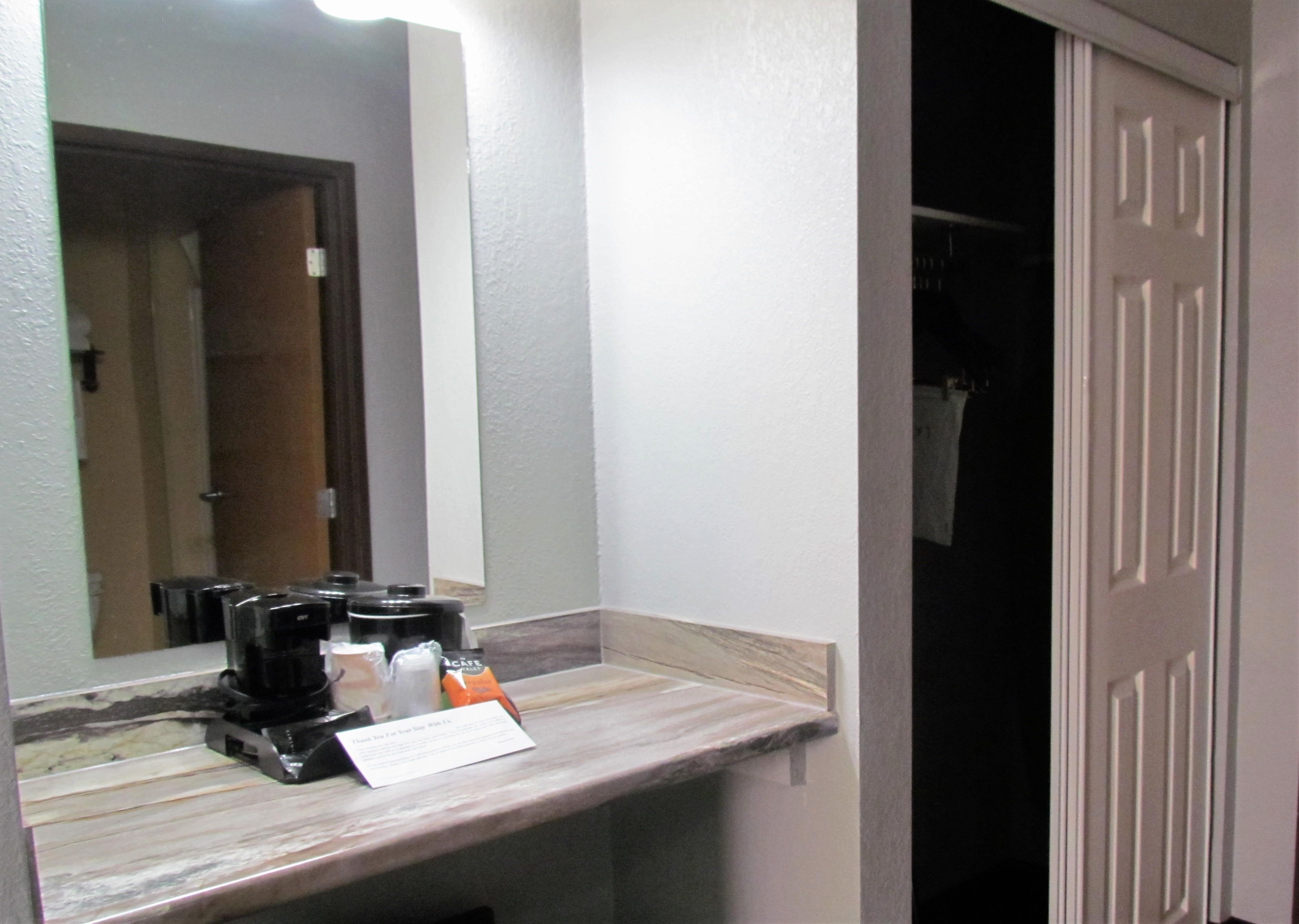 A bathroom with a marble countertop, a coffee maker, and a sign.
