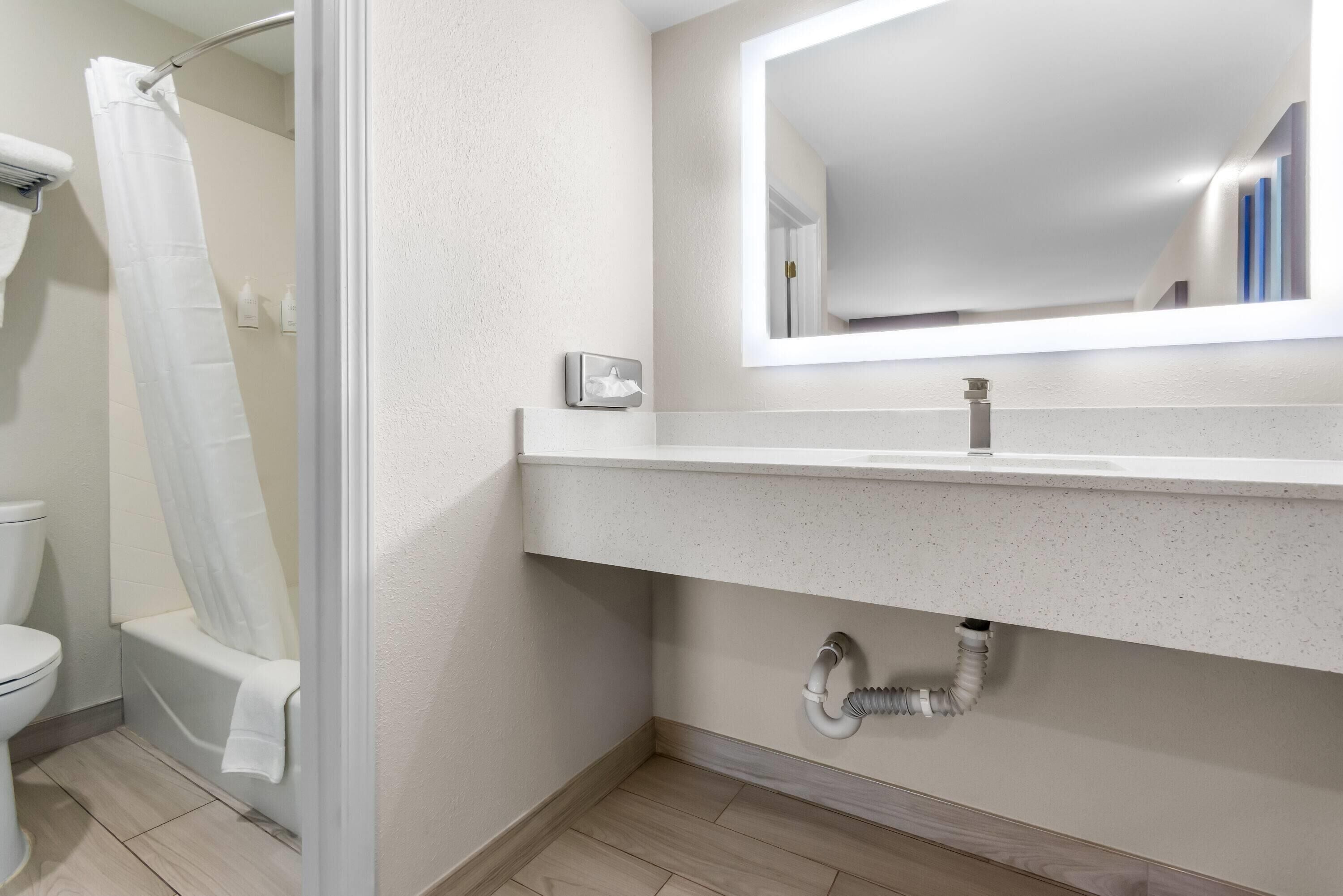 A modern bathroom with a shower, toilet, and sink.