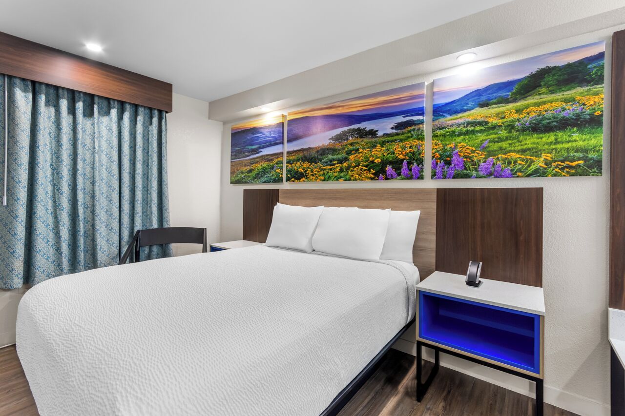 Een moderne hotelkamer met een groot bed, een nachtkastje en een tv aan de muur.