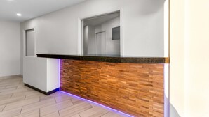 A reception area with a wooden counter, a white wall, and a door.