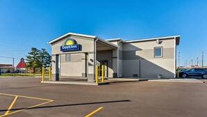 A Days Inn by Wyndham with a simple, functional design, featuring a prominent sign, a covered entrance, and a parking lot.
