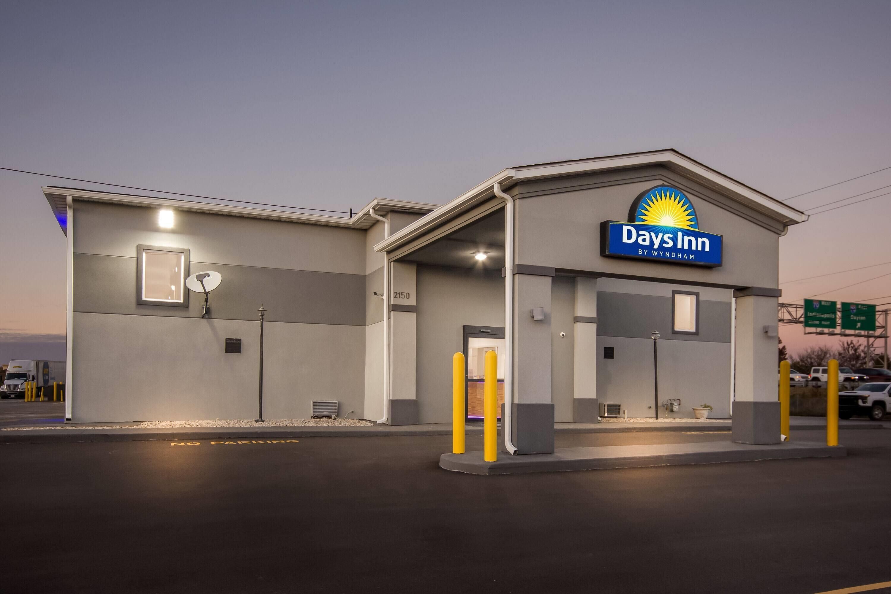 A Days Inn by Wyndham hotel with a 'No Parking' sign, a satellite dish, and a well-lit entrance.