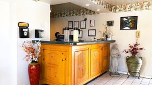A reception area with a wooden counter, a statue, and various framed certificates on the wall.