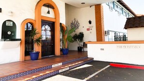 A hotel entrance with a black door, orange arches, and a 'Park to Register' sign.