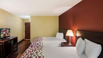 Una habitación de hotel con una cama, un televisor, una lámpara y una alfombra a cuadros.
