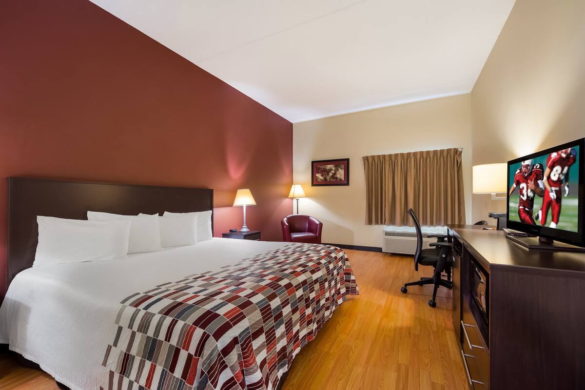 Een hotelkamer met een groot bed, een bureau met een computer, een televisie en een stoel.