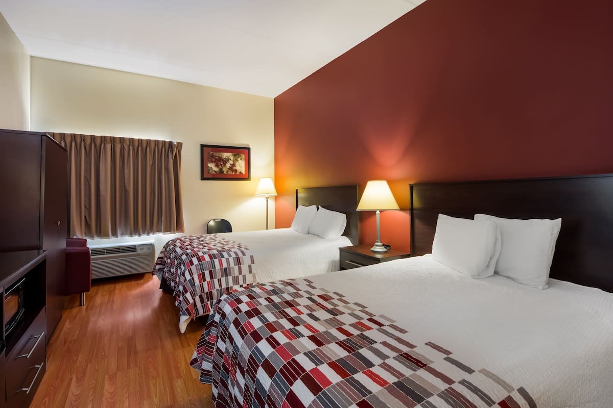 Een hotelkamer met twee bedden, een televisie, een bureau en een raam met gordijnen.