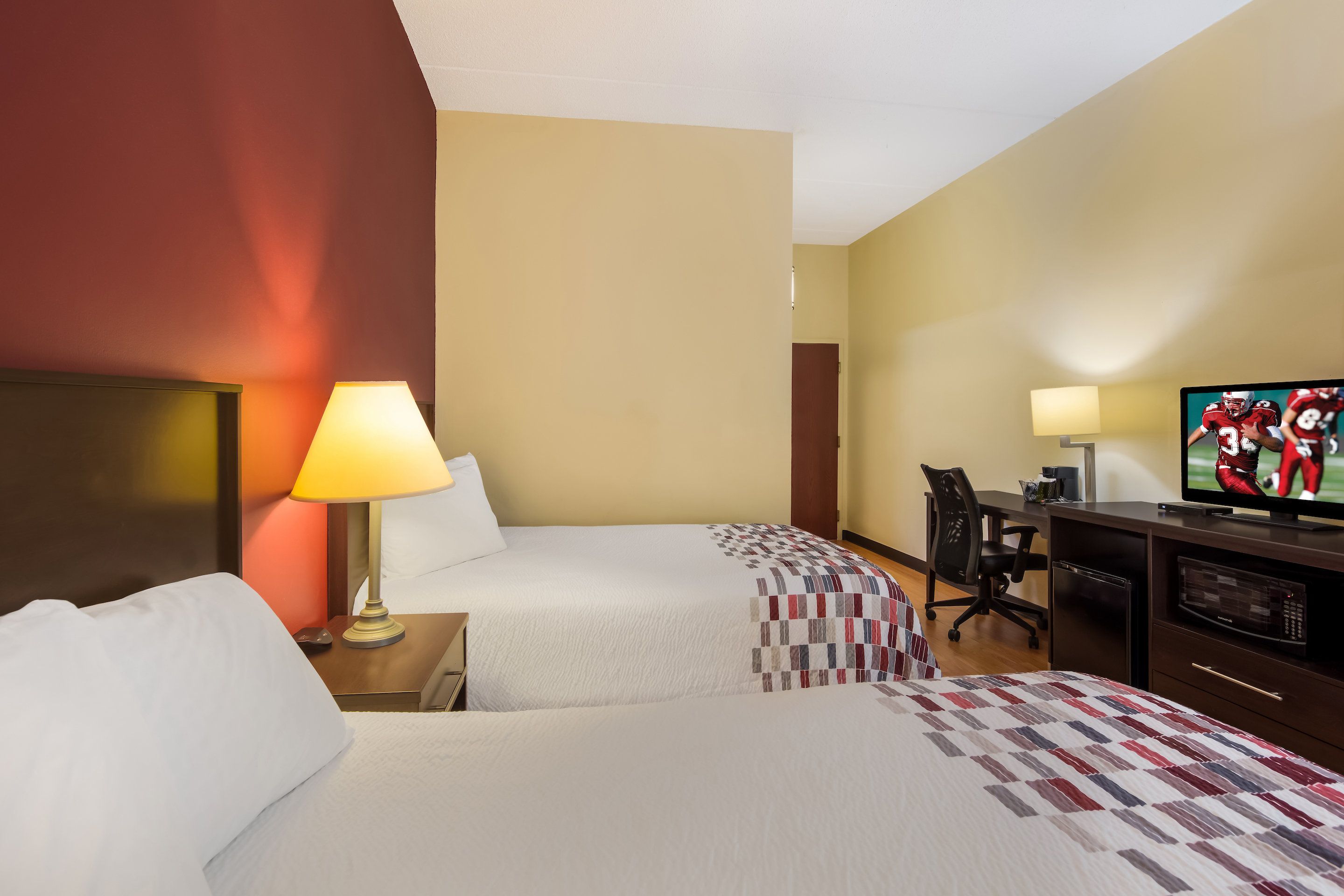 Une chambre d’hôtel avec deux lits, un bureau, une télévision et une lampe.