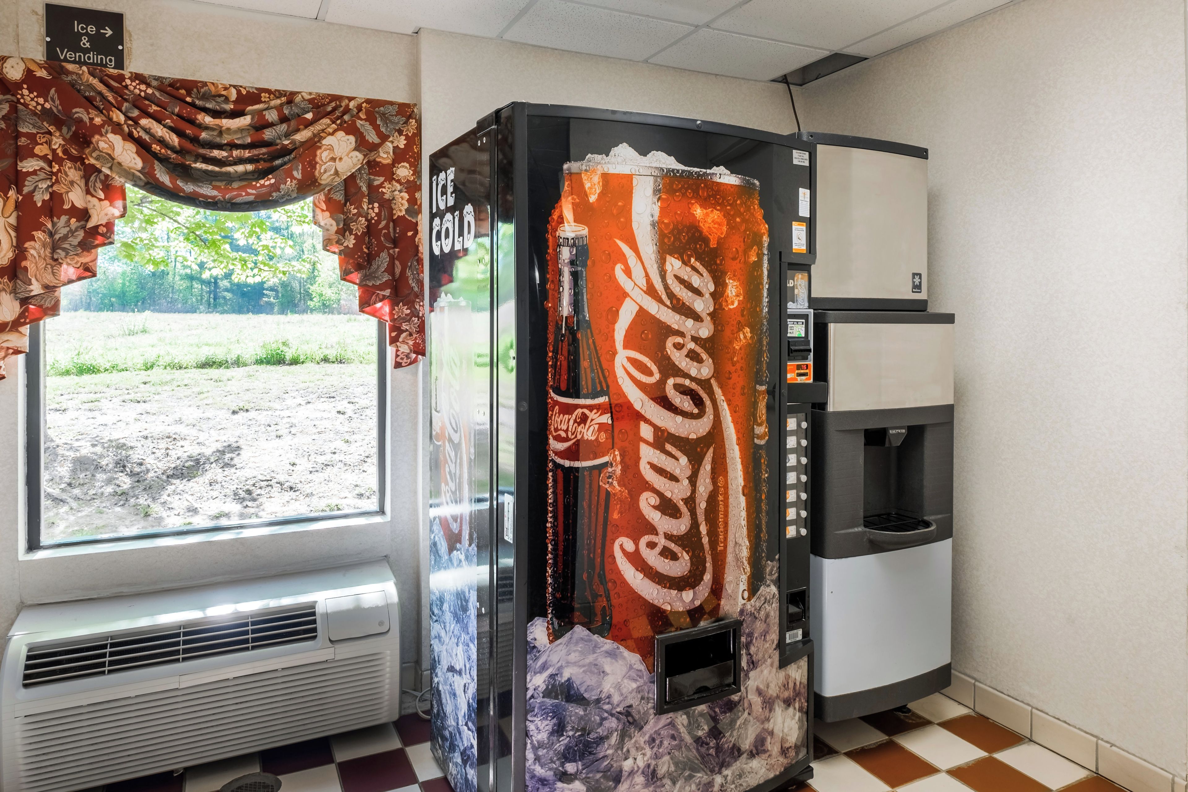 Una máquina expendedora con el logotipo de Coca-Cola, un dispensador de agua y un equipo de aire acondicionado.