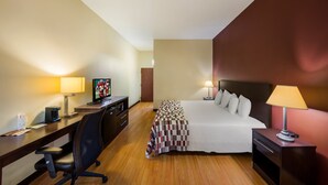 Une chambre d’hôtel équipée d’un lit, d’un bureau, d’une chaise, d’une télévision et de lampes de chevet.
