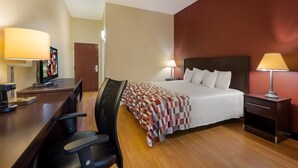 Ein Hotelzimmer mit Bett, Schreibtisch, Stuhl und zwei Nachttischlampen.