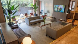 A modern living room with a sofa, armchairs, a coffee table, and a TV. - Hotel Casa Spark Santiago (Santiago)