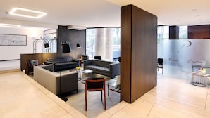 A modern hotel lobby with a grey sofa, a coffee table, and a small dining area. - Hotel Casa Spark Santiago (Santiago)