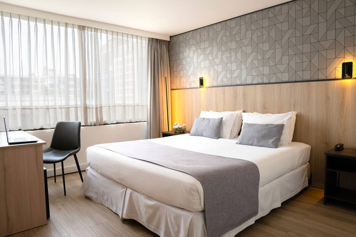 Una habitación de hotel moderna con una cama grande, un escritorio y una silla.