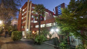 A hotel with multiple floors, a well-lit entrance, and a variety of plants around the building. - Hotel Casa Spark Santiago (Santiago)
