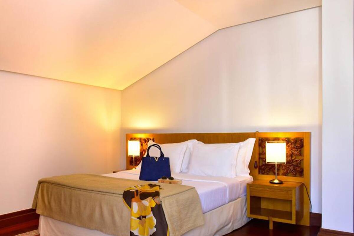 A hotel room with a bed, bedside tables, and a wall-mounted artwork.