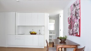 A modern kitchen with white cabinets and a dining area with a wooden table and chairs. - Casa Melo Alvim by Unlock Hotels (Viana do Castelo)