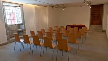 A conference room with rows of wooden chairs and a table covered with a red cloth.