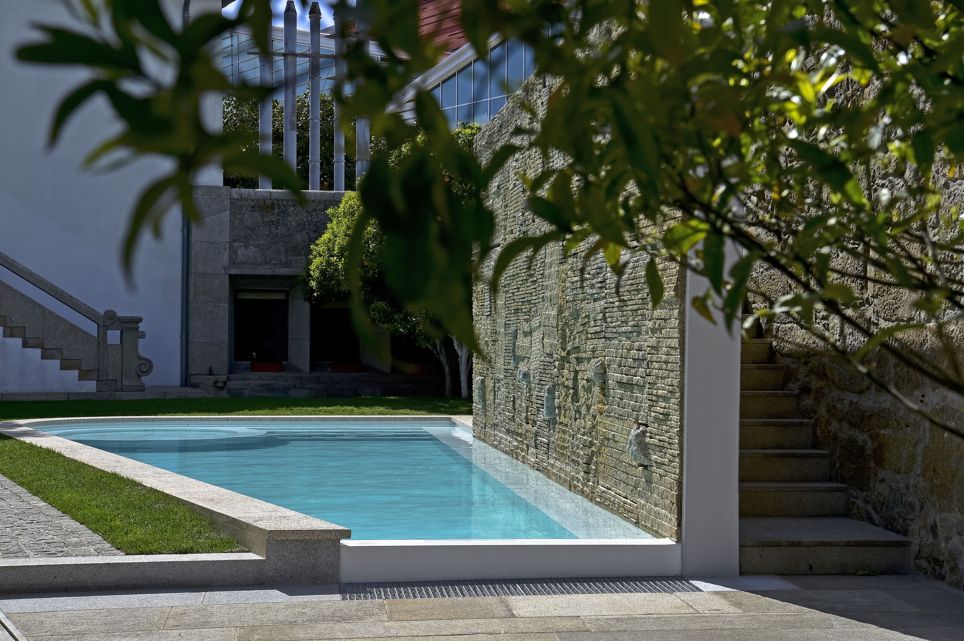 Una piscina con muros de piedra y una escalera que lleva a un edificio.