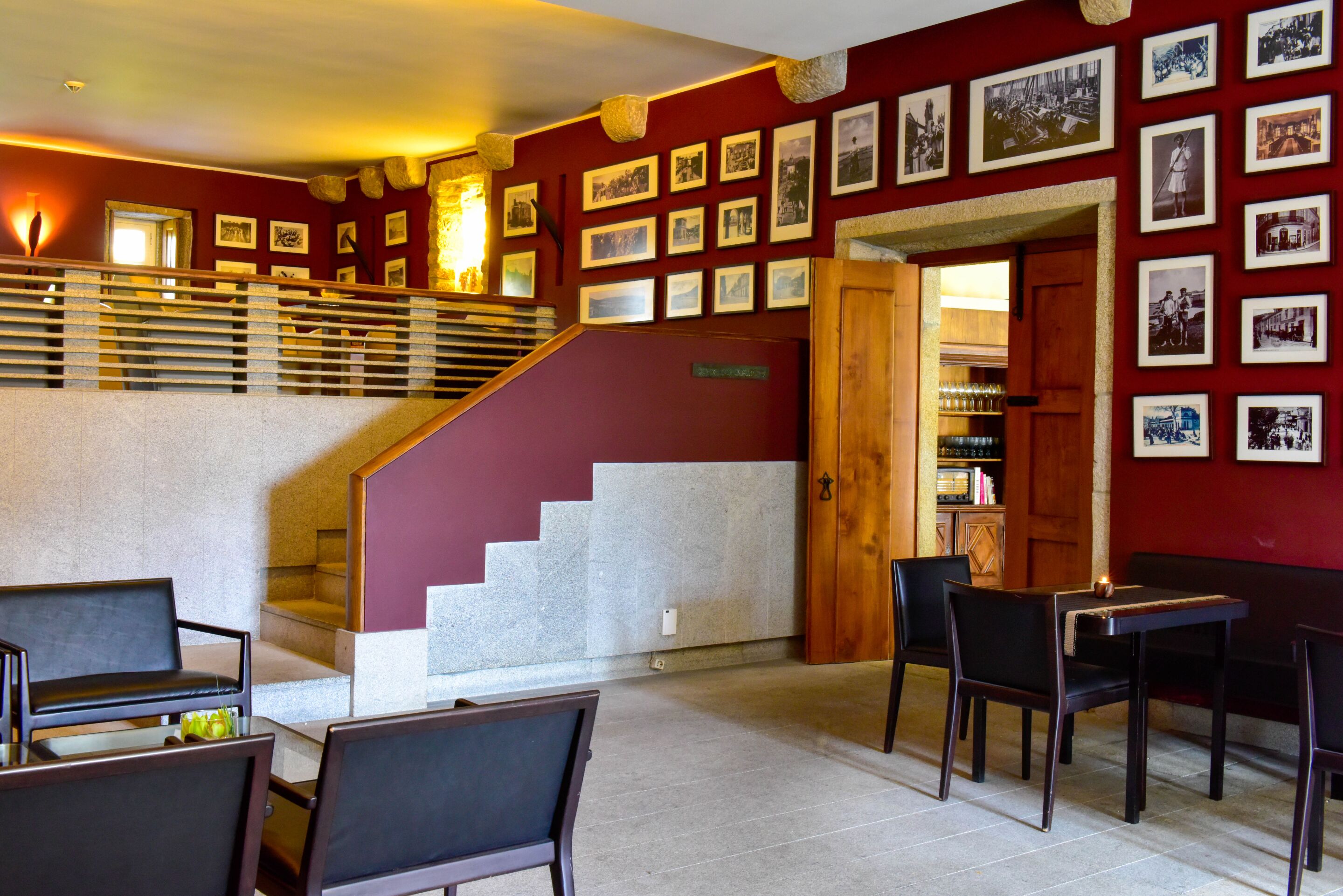 Un vestíbulo de hotel con una escalera, una zona de estar y fotografías colgadas en la pared.