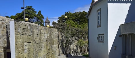 A swimming pool surrounded by a stone wall and a white building with a tiled roof.