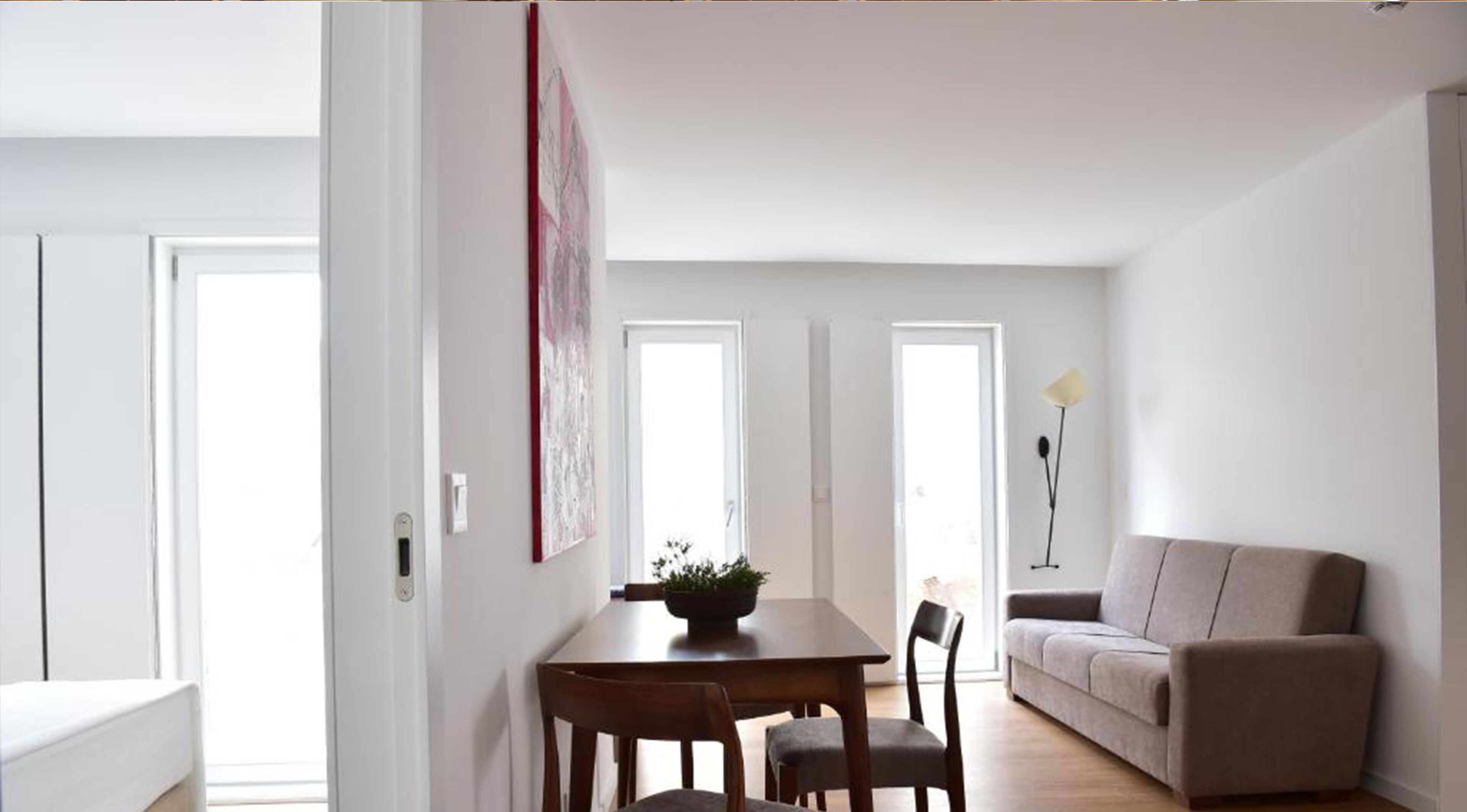 A modern living room with a sofa, a dining table with chairs, and a floor lamp.