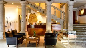 A lobby with stone columns, leather sofas, a reception desk, and a staircase. - Casa Melo Alvim by Unlock Hotels (Viana do Castelo)