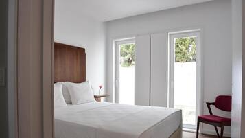 A bedroom with a bed, a wooden headboard, a nightstand, a red chair, and a sliding glass door leading to an outdoor area.