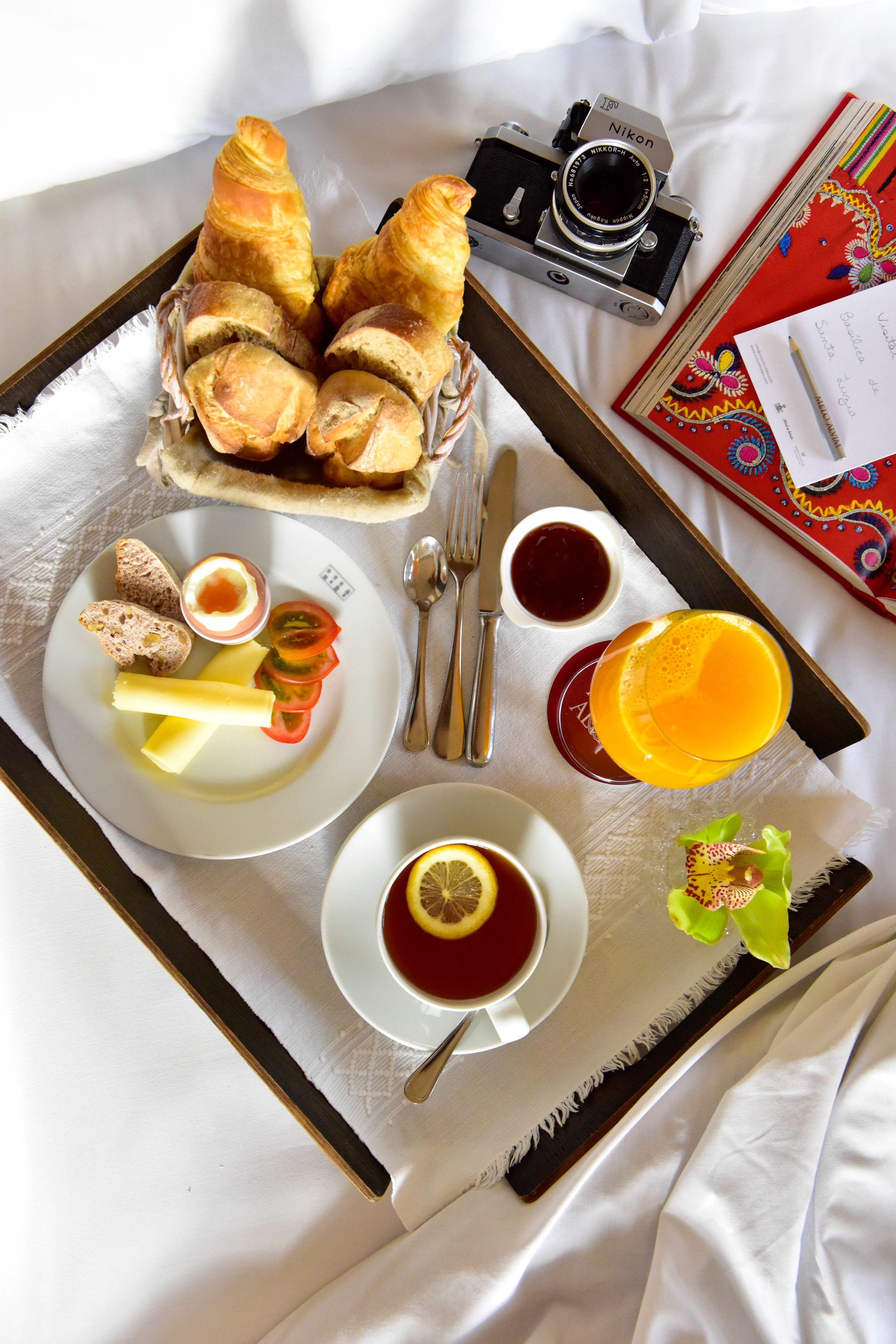 Ein Frühstücksbrett mit Croissants, Brot, Käse, Tomaten und einem Glas Orangensaft.