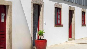 Un edificio con paredes blancas y puertas rojas, con una planta en maceta al frente.