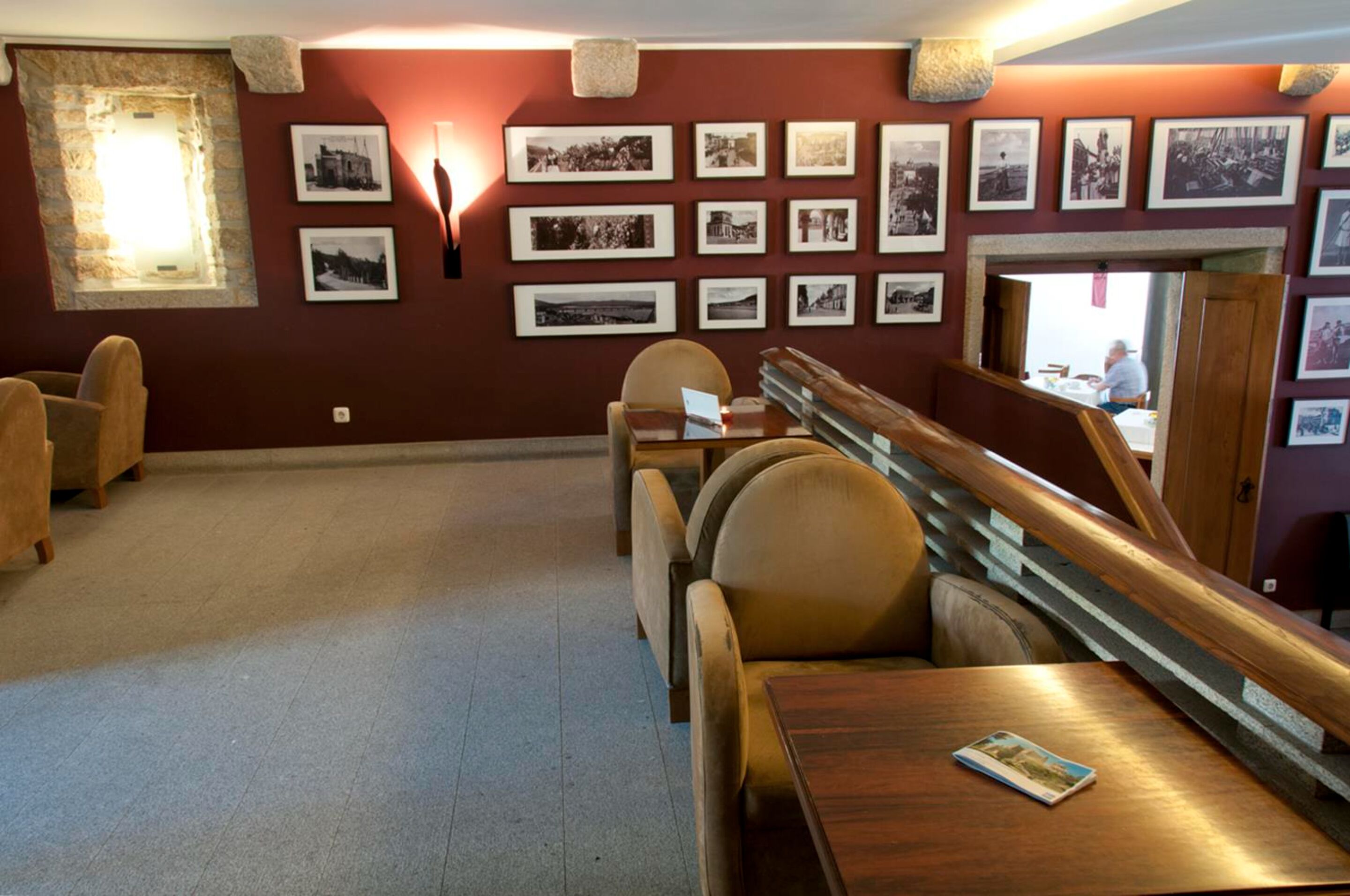 Una habitación con un largo banco de madera, una mesa y una pared decorada con fotografías blanco y negro enmarcadas.