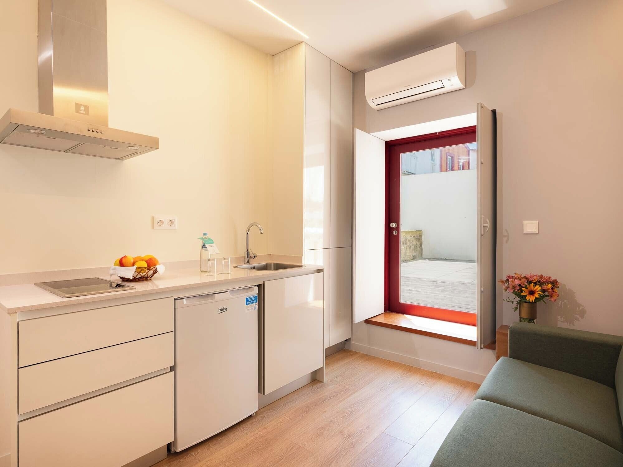 A compact kitchen with a dishwasher, a sink, and a window with a red frame.