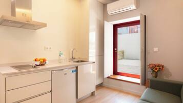 A compact kitchen with a dishwasher, a sink, and a window with a red frame.