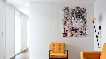 Una sala de estar moderna con un cuadro abstracto grande, dos sillones amarillos y una lámpara de pie.