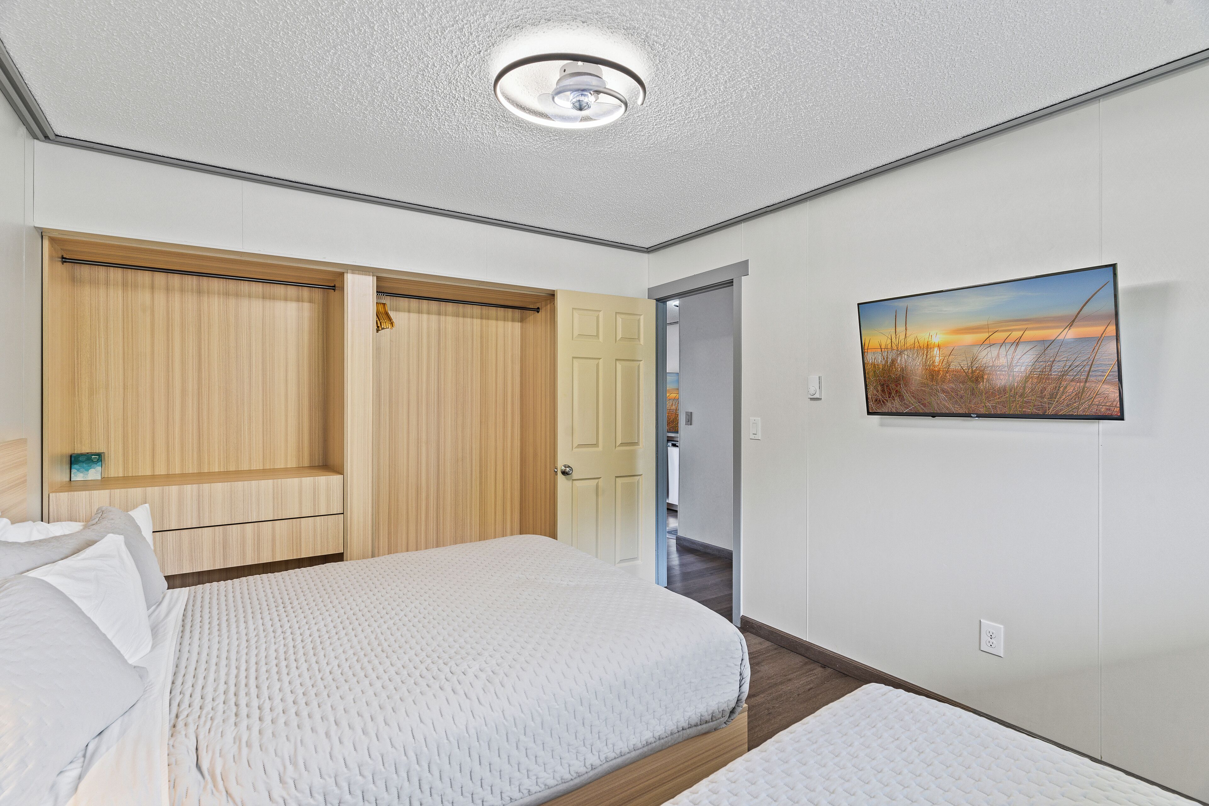 A bedroom with a bed, a wardrobe, a door, and a painting on the wall.