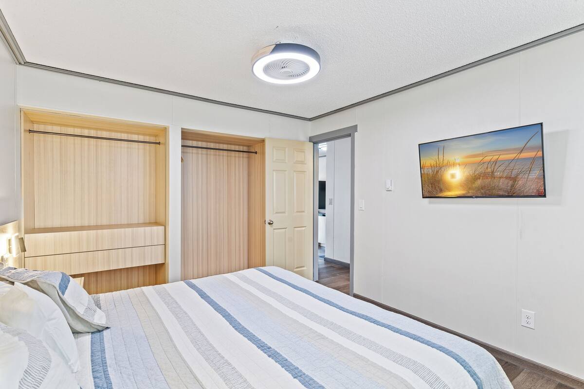 Un dormitorio con cama, un armario de madera, una puerta y un cuadro en la pared.