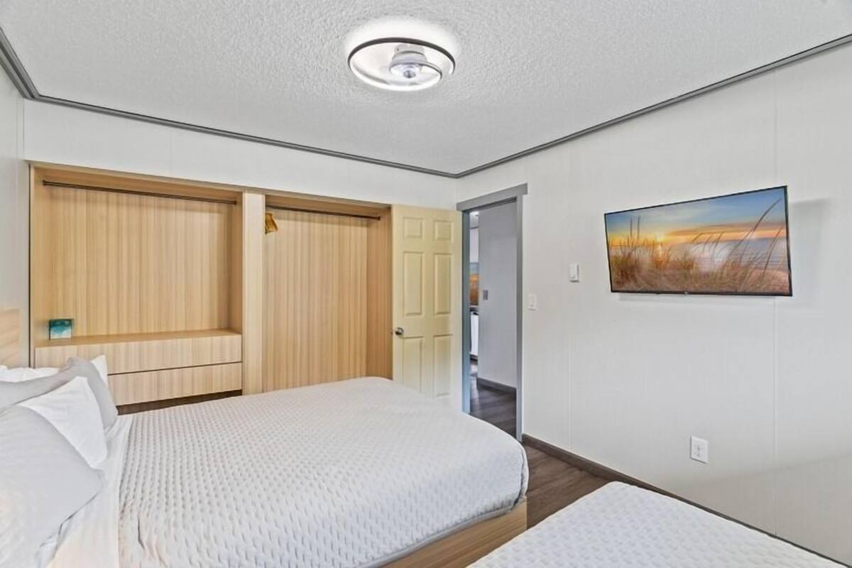 Un dormitorio con cama, armario, puerta y un cuadro en la pared.