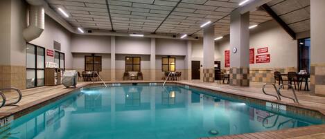 An indoor swimming pool with clear water, surrounded by tiled walls and a tiled floor.