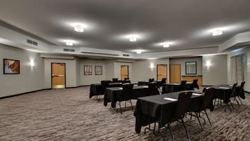 Un salón de conferencias con mesas y sillas, una alfombra estampada e iluminación empotrada.