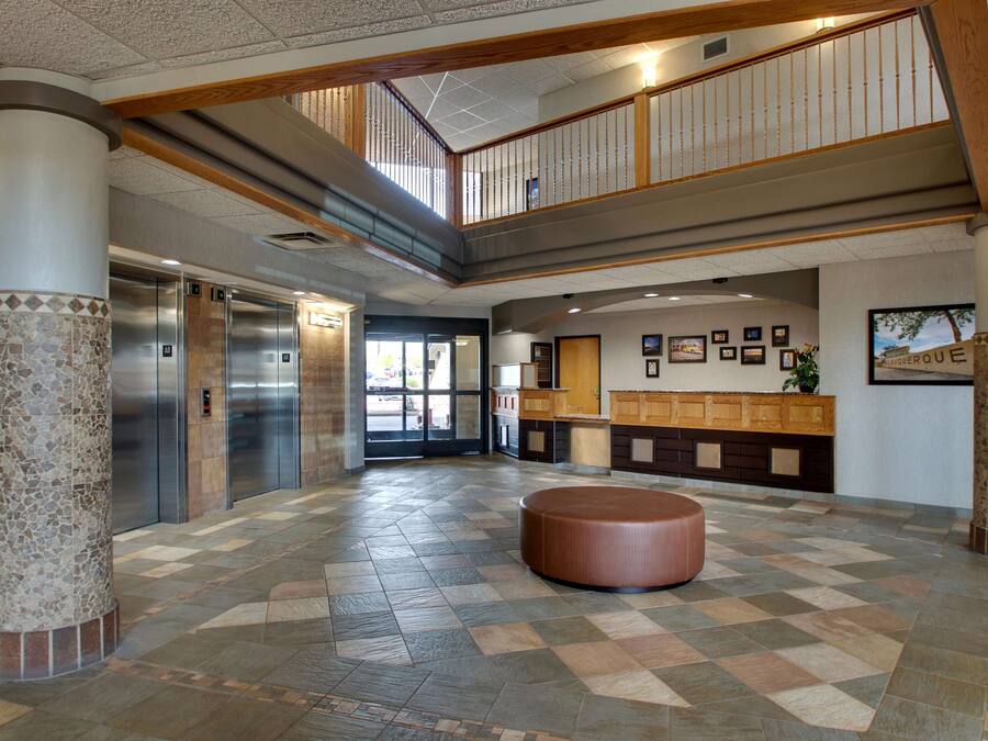 A spacious lobby with a checkered floor, a central seating area, and a reception desk.