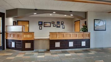 A reception area with a check-in counter, framed pictures on the wall, and a patterned floor.
