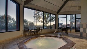 Ein Wellnessbereich mit Whirlpool, großen Fenstern und Sitzgelegenheiten im Freien.