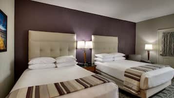 Une chambre d’hôtel avec deux lits, une tête de lit, des lampes de chevet et un tableau encadré au mur.