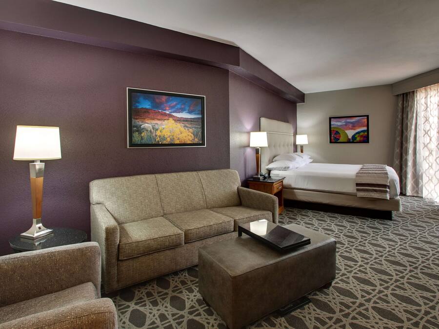 Ein Hotelzimmer mit einer Couch, einem Couchtisch, einem Bett und zwei Bildern an der Wand.