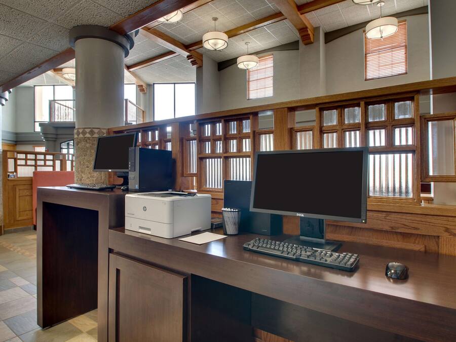 A reception desk with two monitors, a printer, and a keyboard.