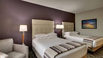 A hotel room with two beds, a sofa, and two bedside lamps.